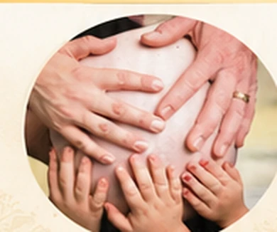 Family hands resting gently together on an expectant mother's belly